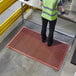 A person standing on a red Lavex anti-fatigue floor mat.
