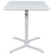A white square Luxor pneumatic adjustable height cafe table with a white base.