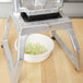 A metal bowl with chopped onions from a Vollrath Redco InstaCut 3.5 Fruit and Vegetable Dicer sitting on a table.
