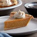 A slice of pumpkin pie with whipped cream on top.