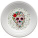 A Fiesta luncheon plate with a skull and vine design in white.