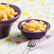 A mulberry Fiesta china bowl filled with macaroni and cheese on a pink napkin.