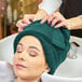 A woman with a hunter green Monarch Brands hand towel wrapped around her head.
