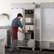 A man opening the white doors of a Beverage-Air Horizon Series reach-in freezer.