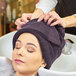 A woman with a Monarch Brands eggplant hand towel on her head while getting her hair washed.
