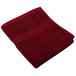 A burgundy Monarch Brands hand towel folded on a white background.