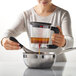 A woman using an OXO Good Grips fat separator to pour brown liquid into a bowl.