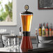 A Beer Tubes woodgrain conic beer tower dispenser on a table with two glasses.
