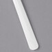 A close-up of a white rectangular Dart plastic spoon on a gray surface.