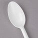 A Dart white plastic spoon with a white handle on a gray surface.
