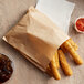 A Carnival King extra large kraft paper bag of fried food next to a cup of brown liquid and a bowl of red sauce.