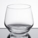 A clear Chef & Sommelier rocks glass on a reflective surface.