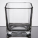 A square clear glass Libbey condiment jar on a reflective surface.
