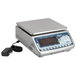 An Edlund stainless steel digital portion scale with a power cord on a counter.