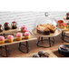 A Madison Avenue antique brass oval stand with cakes and cupcakes on a wooden table.