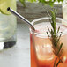 A Barfly stainless steel bent straw in a glass of lemonade with a rosemary sprig.