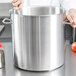 A woman holding a Vollrath stainless steel stock pot.