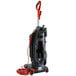 A Hoover bagged upright vacuum cleaner with a red tube.