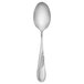 A close-up of a Walco Goddess stainless steel serving spoon with a curved handle.