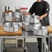 A man in a chef's uniform standing in front of a Choice aluminum brazier.