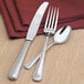 A Libbey stainless steel salad fork and knife on a napkin.