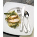 A plate of food with chicken, green beans, and a Libbey stainless steel dessert spoon.