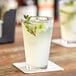 A close-up of an Acopa highball glass filled with liquid, ice, and mint leaves.