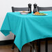 A table with a teal Intedge tablecloth and a plate of food.