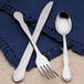 A Libbey stainless steel salad fork on a blue cloth napkin.