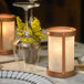 A table set with a wine glass and a Sterno Copper Frost votive candle holder with a lit candle.