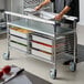 A man using a Metro stainless steel kitchen cart to prepare food.