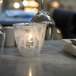 A Sterno Helix Whisper Votive candle holder with a lit candle on a table in an Italian restaurant.