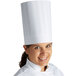 A woman wearing a white Mercer Culinary chef trek toque hat.
