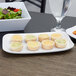 A white Siciliano rectangular platter with mini quiches and salad on it.