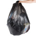A person holding a large black Berry trash bag.