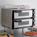 A Waring countertop pizza oven with two pizzas cooking inside.