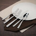 A white plate with a Walco stainless steel salad fork on it.