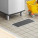 A floor trough with a grate and a yellow bucket on the floor.
