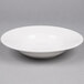 A Tuxton Alaska bright white china soup/pasta bowl with a spoon in it.