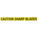 A yellow rectangular caution sign with black text that reads "Caution: Sharp Blades"