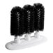 A Noble Products triple bar glass washer with three black bristle brushes on a white stand.