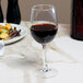 An Arcoroc Excalibur Breeze wine glass filled with red wine on a table