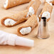 A group of cannoli with cream filling next to a pastry bag with an Ateco Plain Piping Tip.