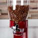 A red and clear Zevro dry food dispenser filled with brown cereal.