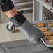A person wearing a SafeMitt glove holding a tray of cookies.