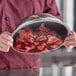A person using Choice Foodservice Film to cover a bowl of meat on a counter.