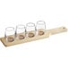 An Acopa wooden flight paddle with four stemless wine glasses on it.