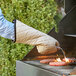 A person using 17" flame retardant oven mitts to cook burgers on a grill.