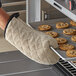 A person wearing 13" terry oven mitts holding a cookie baking tray of cookies.