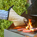 A person wearing flame retardant oven mitts cooking burgers on a grill.